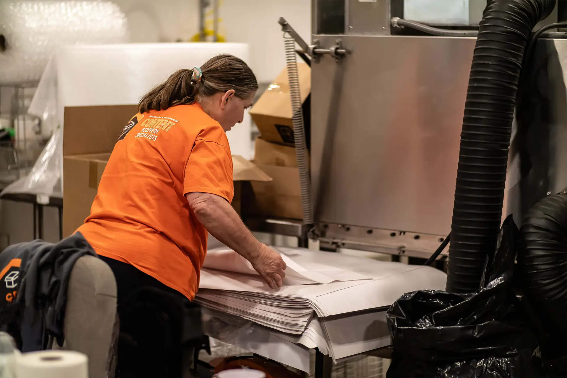A woman in a CRS orange shirt looking at a stack of wrapping paper