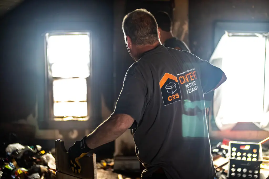 A CRS employee in a dark room with a window working to restore home contents